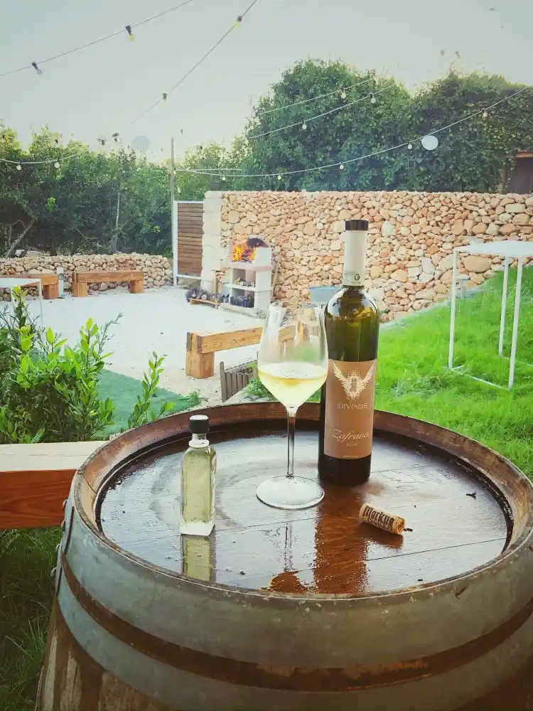 A glass and bottle of Markus Divinus wine resting on an oak barrel