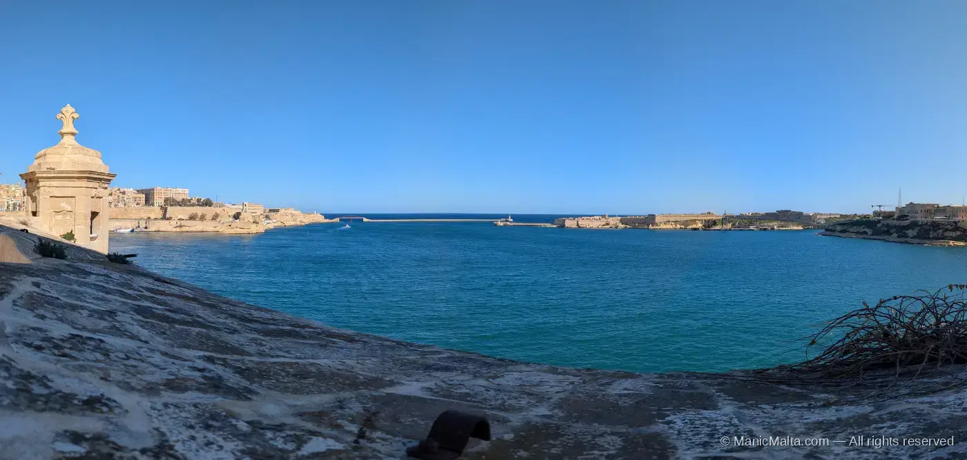 Panoramic view across the Grand Harbour from a low bastion at Fort St Angelo, with a stone Vedette guardpost on the left and the harbour entrance visible in the distance
