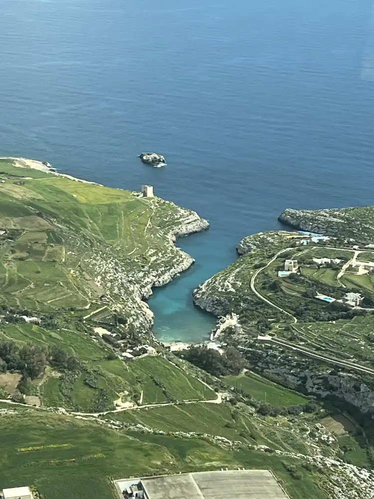 A small bay on the Gozo coast with a coastal watchtower on the headland, seen from a small aircraft