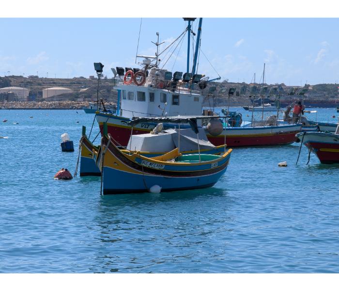 A pair of traditional Maltese luzzu boats with the painted eye of Osiris on each bow, moored close to the Marsaxlokk waterfront