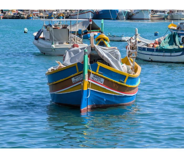 The Mario, a Valletta-registered luzzu, photographed head-on in Marsaxlokk harbour with other boats moored in the background